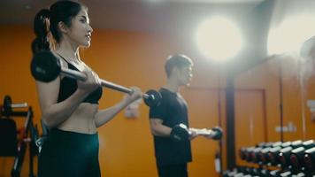 starke Frau, die während des Cross-Trainings im Fitnessstudio mit persönlichem Trainer Langhantelkniebeugen macht video