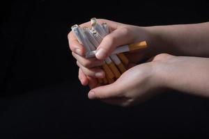 Hand is giving out bundle of cigarettes on black photo