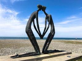 Abstract statues, small architectural forms of people in love in the form of a kneeling knee on the Batumi Primorsky Boulevard or Batumi Beach. Georgia, Batumi, April 17, 2019 photo