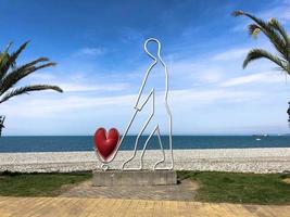 Abstract statues, small architectural forms of a man carrying a heart on a trolley on Batumi Seaside Boulevard or Batumi Beach. Georgia, Batumi, April 17, 2019 photo