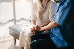 Close up view of old woman leaning on nurse while siting photo