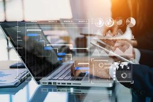Businessman hand Project manager working and update tasks and Gantt chart scheduling virtual diagram.with smart phone, tablet and laptop in office. photo