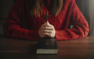 mujer sentada y estudiando las escrituras. la cruz de madera en las manos. conceptos de educación cristiana las sagradas escrituras abiertas foto