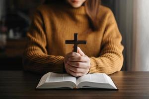 Woman sitting and studying the scriptures.The  wooden cross in the hands. Christian education concepts The Holy Scriptures open and pray photo