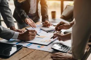 Business documents on office table with smart phone and calculator digital tablet and graph business with social network diagram and two colleagues discussing data working in the office photo