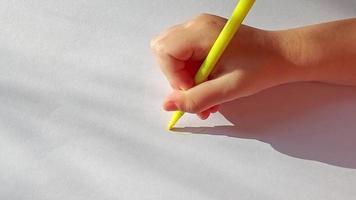 sun hand draws with a felt-tip pen on a white sheet of paper. childrens creativity, naive drawing. video