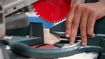 professional woodworker cutting wooden plank with miter saw in carpentry workshop