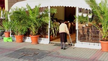 une femme balaie le trottoir d'un magasin video