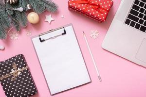 Blank paper on tablet and Cristmas New Year work table decoration top view, flat lay on pink background photo
