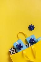 Christmas presents for the holidays concept. Holiday gift boxes with bows in a shopping bag on a color background photo