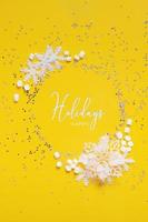 Happy Holidays text in frame made from snowflakes, marsh mellow and puansettia on yellow background. Vertical forma photo