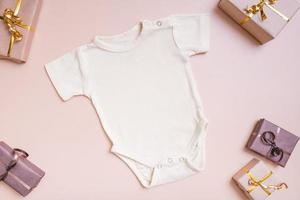 maqueta de ropa de bebé para logotipo, texto o diseño en fondo beige con vista superior de decoraciones de invierno foto