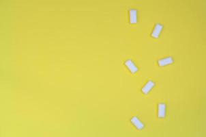 A few chewing gums lie on texture background of fashion pastel yellow color paper in minimal concept photo