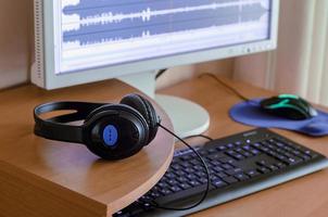 Big black headphones lie on the wooden desktop of the sound designer photo