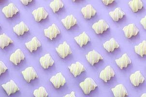 Colorful marshmallow laid out on violet paper background. pastel creative textured pattern. minimal photo