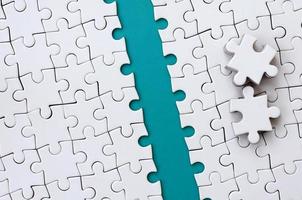 The blue path is laid on the platform of a white folded jigsaw puzzle. The missing elements of the puzzle are stacked nearby. Texture image with space for text photo