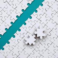 The blue path is laid on the platform of a white folded jigsaw puzzle. The missing elements of the puzzle are stacked nearby. Texture image with space for text photo