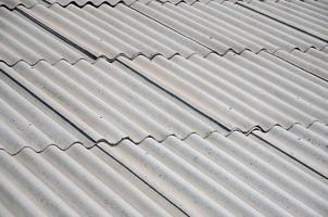 A fragment of a gray slate roof of an old sample made of asbestos material photo
