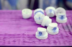 las boquillas azules sucias del rociador de pintura se encuentran en un tablón morado sobre un fondo de muchas latas de aerosol sucias foto
