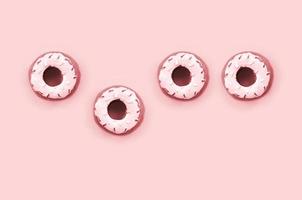 Many small plastic donuts lies on a pastel colorful background. Flat lay minimal pattern. Top view photo