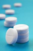 A few white tablets lie on a bright blue background surface. Background image on medical and pharmaceutical topics photo