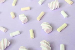 Colorful marshmallow laid out on violet paper background. pastel creative textured pattern. Perspective macro shot photo