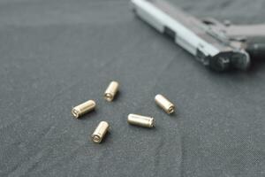 9mm bullets and pistol lie on a black fabric. A set shooting range items or a self-defense kit photo