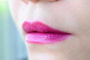 Close up shot of woman lips with glossy fuchsia lipstick photo