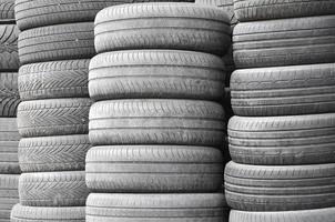 Old used tires stacked with high piles in secondary car parts shop garage photo