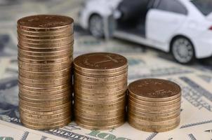 Toy car model at the stacks of golden coins lies on many dollar bills photo