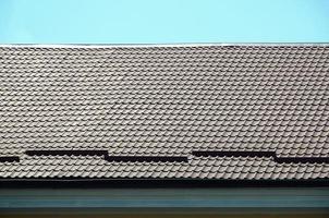 A fragment of a roof from a metal tile of dark red color. Quality Roofing photo