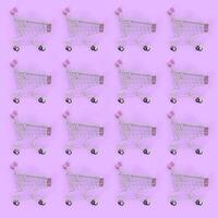 Shopping addiction, shopping lover or shopaholic concept. Many small empty shopping carts perform a pattern on a pastel colored paper background. Flat lay composition, top view photo