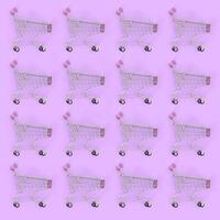 Shopping addiction, shopping lover or shopaholic concept. Many small empty shopping carts perform a pattern on a pastel colored paper background. Flat lay composition, top view photo