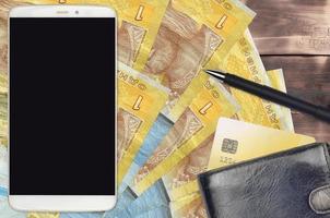 1 Ukrainian hryvnia bills and smartphone with purse and credit card. E-payments or e-commerce concept. Online shopping and business with portable devices photo