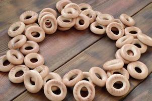 A lot of fresh yellow bagels lie on the surface of the old dark wood. A popular kind of flour products. One of the traditional Russian treats for tea photo