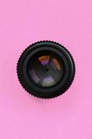 Camera lens with a closed aperture lie on texture background of fashion pastel pink color paper in minimal concept photo