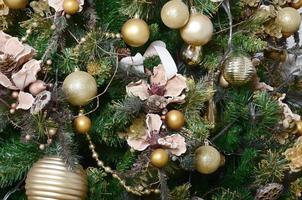 Decorating Christmas tree close up. Decoration bulb, green fir tree, golden x-mas toys and lights. Use for Christmas and New years celebration background photo