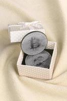 The silver bitcoin lies in a small orange gift box with a small bow on a blanket made of soft and fluffy light orange fleece fabric with a large number of relief folds photo