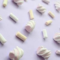 Colorful marshmallow laid out on violet paper background. pastel creative textured pattern. Perspective macro shot photo