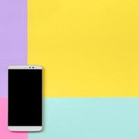 Modern smartphone with black screen on texture background of fashion pastel blue, yellow, violet and pink colors paper in minimal concept photo