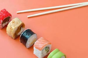 Different types of asian sushi rolls on orange background. Minimalism top view flat lay with Japanese food photo