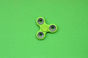 Green fidget spinner lies on texture background of fashion pastel green color paper in minimal concept photo