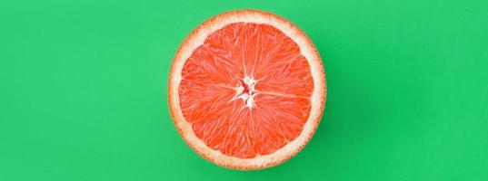 Top view of an one grapefruit slice on bright background in green color. A saturated citrus texture image photo