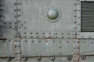 Texture of tank side wall, made of metal and reinforced with a multitude of bolts and rivets photo