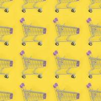 Shopping addiction, shopping lover or shopaholic concept. Many small empty shopping carts perform a pattern on a pastel colored paper background. Flat lay composition, top view photo