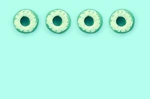 Many small plastic donuts lies on a pastel colorful background. Flat lay minimal pattern. Top view photo