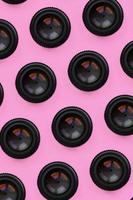 A few camera lenses with a closed aperture lie on texture background of fashion pastel pink color paper in minimal concept. Abstract trendy pattern photo