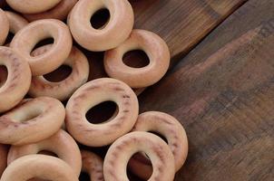 A lot of fresh yellow bagels lie on the surface of the old dark wood. A popular kind of flour products. One of the traditional Russian treats for tea photo