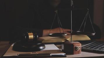 Business and lawyers discussing contract papers with brass scale on desk in office. Law, legal services, advice, justice and law concept picture with film grain effect video