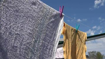 gekleurde handdoeken in beweging in de wind Aan een Kledinglijn Aan een zonnig dag met een blauw lucht video